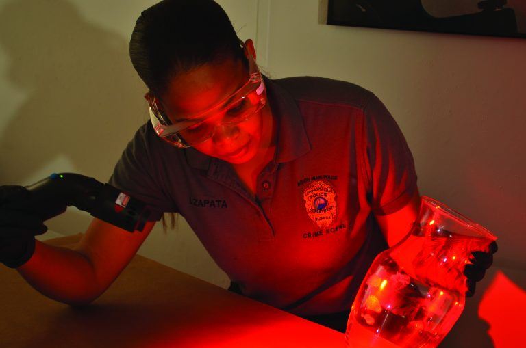 A woman wearing safety glasses examining a vase